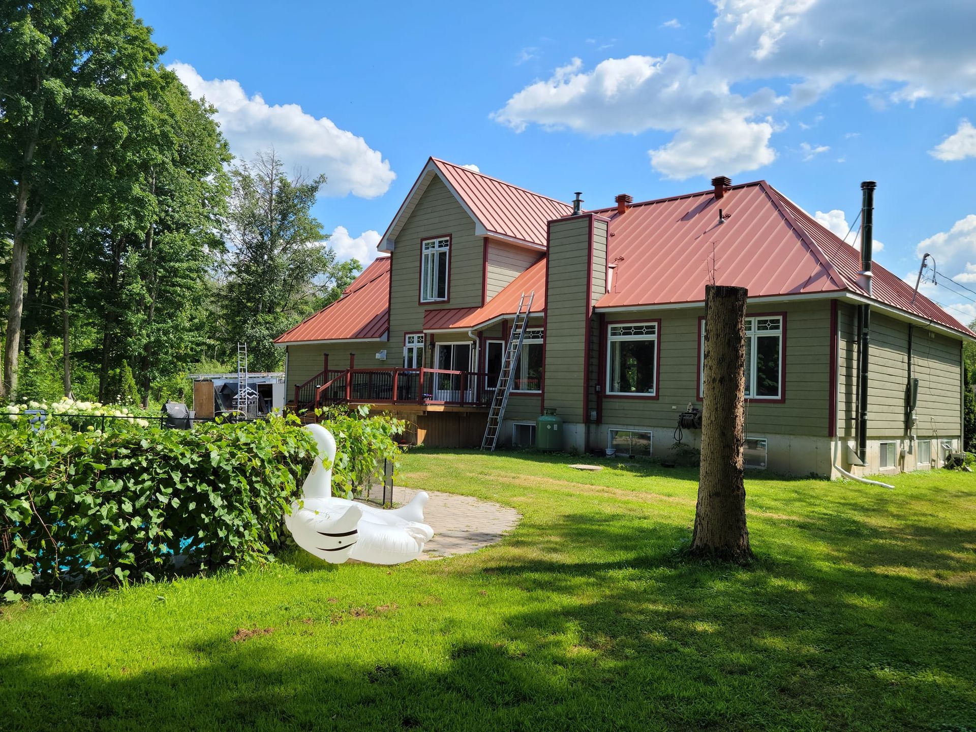 Une grande maison au toit rouge se trouve au milieu d'un champ verdoyant.