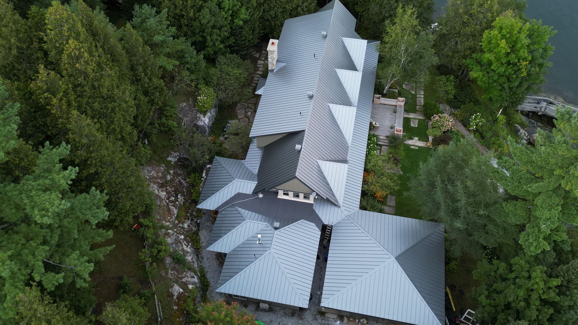 Une vue aérienne d'une grande maison entourée d'arbres et d'un plan d'eau.