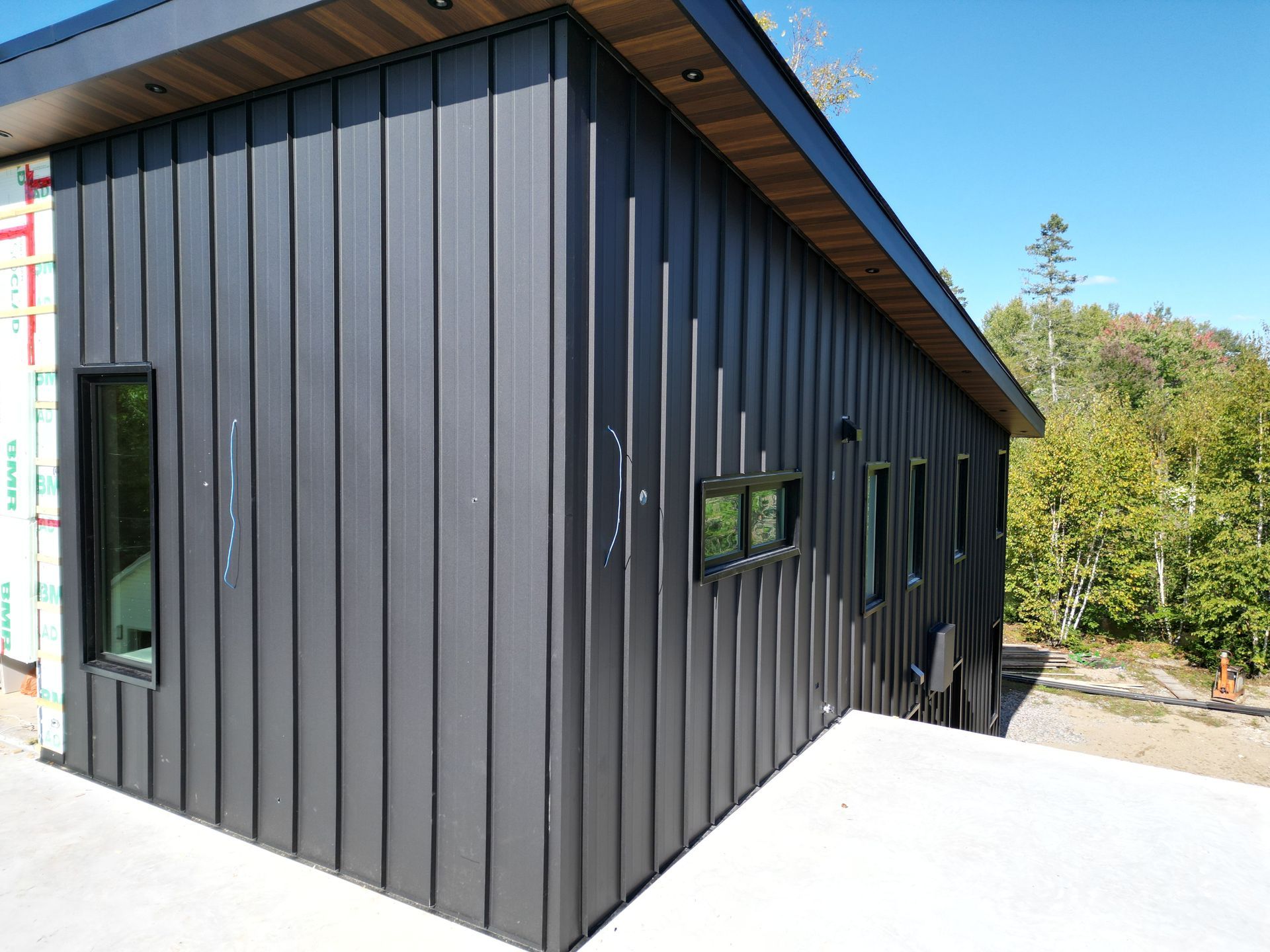 Une maison noire avec beaucoup de fenêtres est en construction.