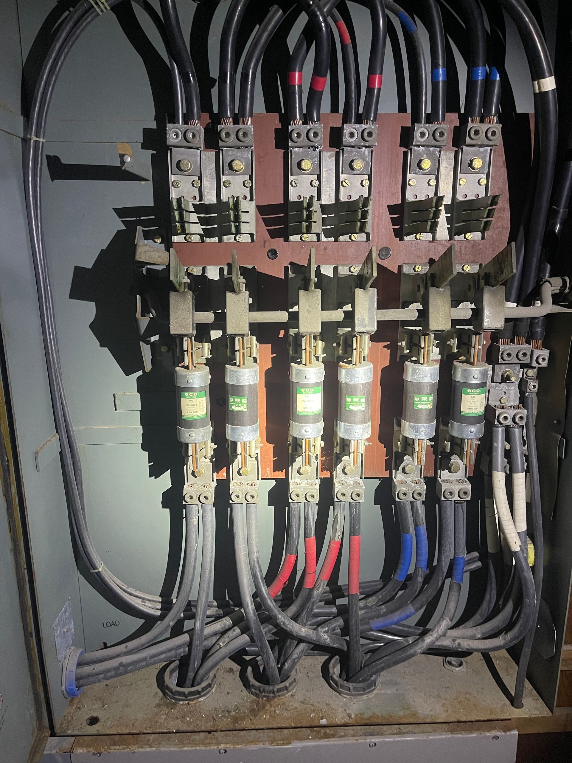 Electrical panel with fuses and wires, primarily dark colors.
