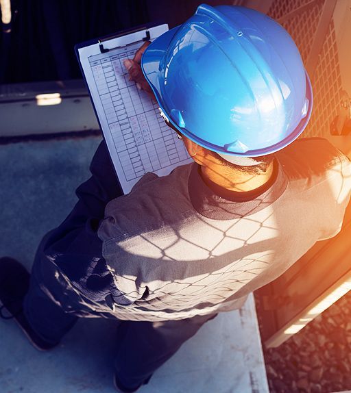 Person in blue hard hat reviews paperwork in a bright setting, possibly outdoors.