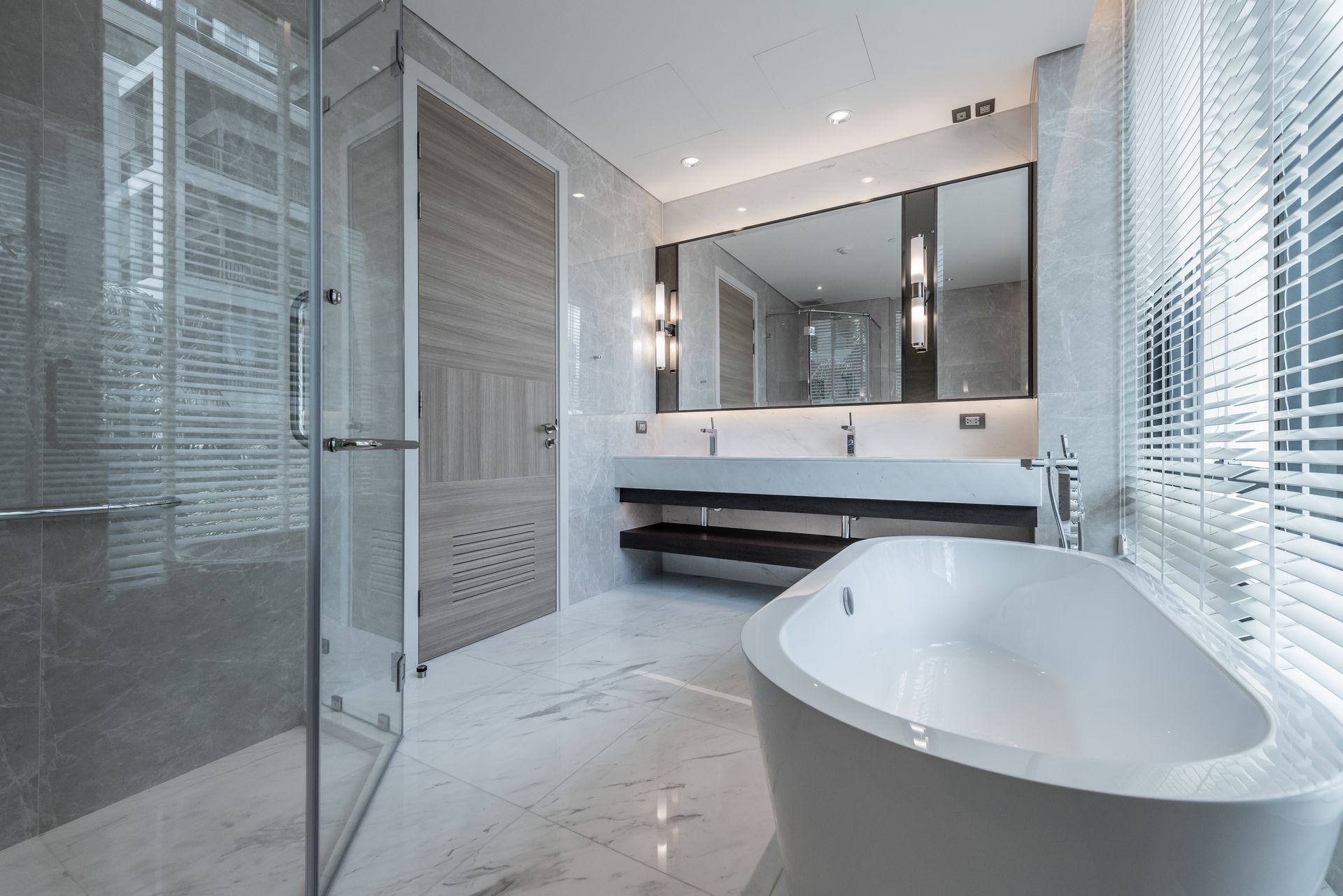 Modern white bathroom with glass shower, freestanding tub, double vanity, and marble floor.