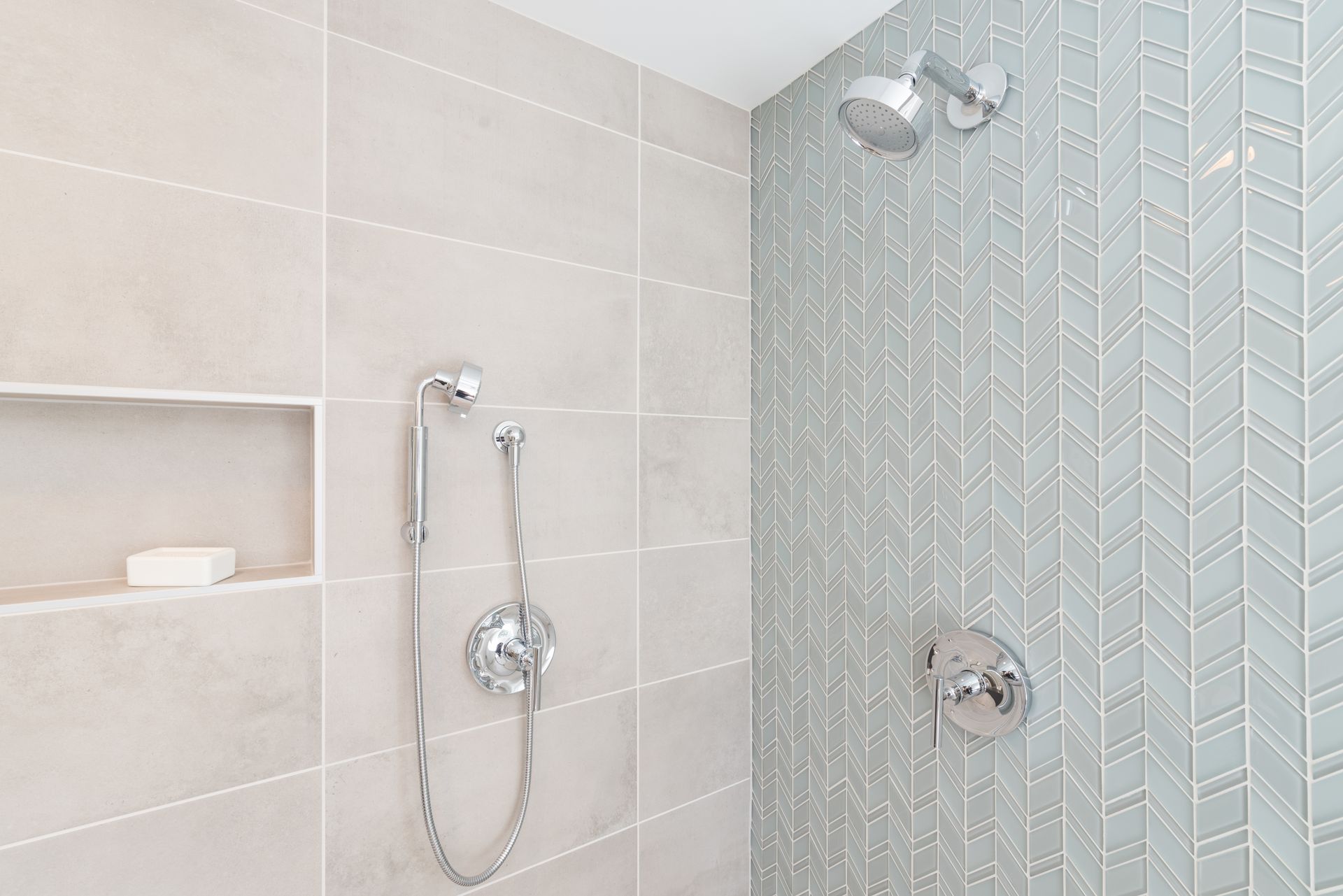 Modern bathroom shower with glass mosaic tile, wall-mounted showerhead, and handheld sprayer