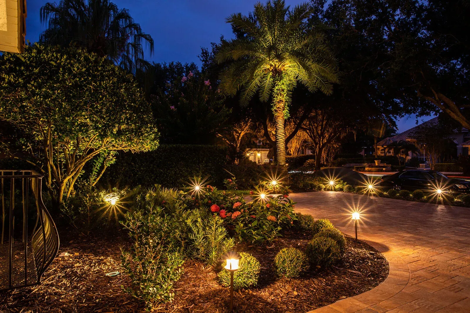 Nighttime garden with illuminated bushes, palm tree, and pathway. Nighttime garden with illuminated bushes, palm tree, and pathway.