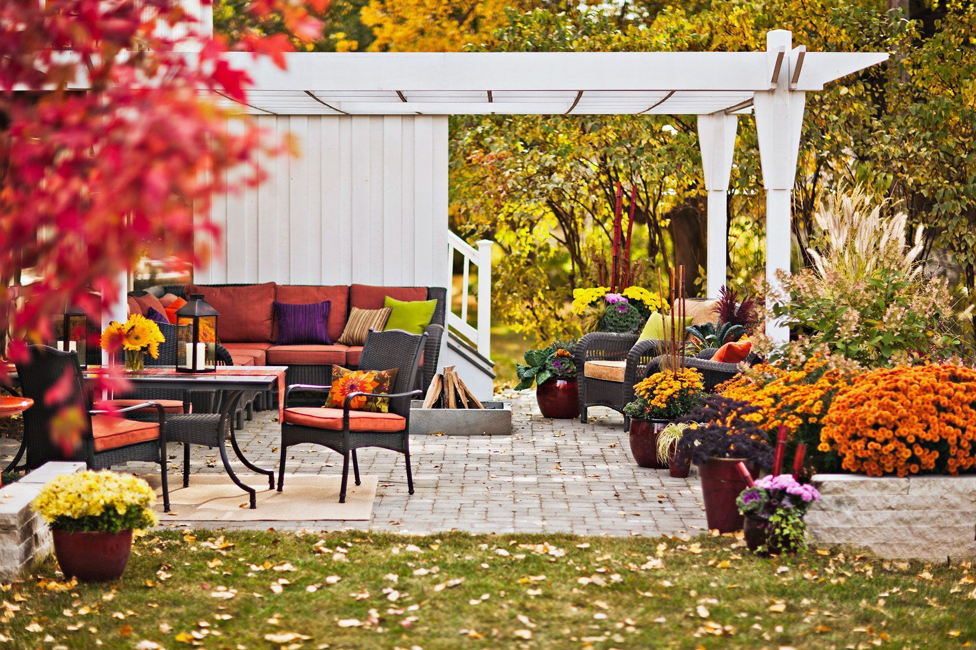 Outdoor patio with furniture, a pergola, and fall foliage; orange, yellow, and red colors dominate. Outdoor patio with furniture, a pergola, and fall foliage; orange, yellow, and red colors dominate.