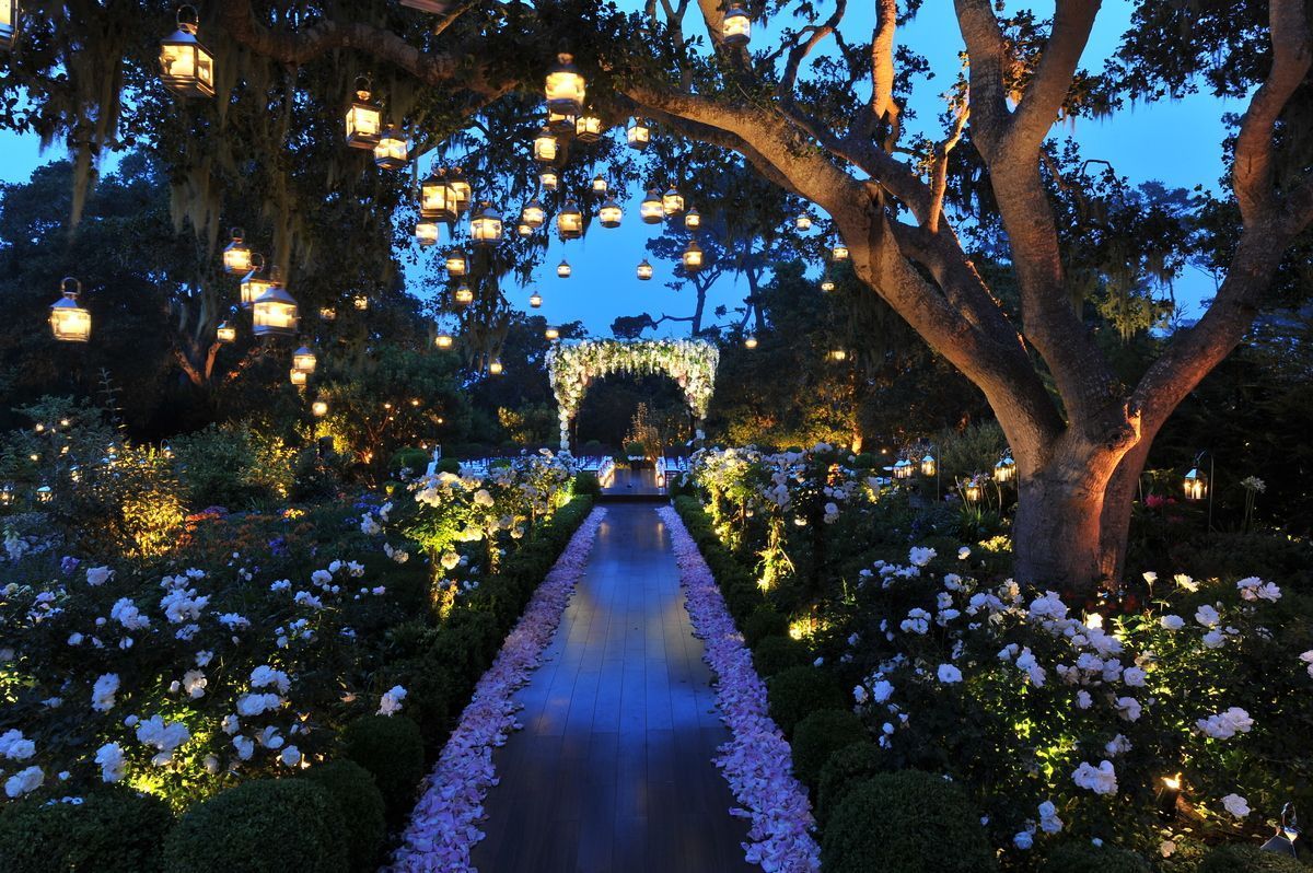 An outdoor garden wedding ceremony at dusk with string lights.