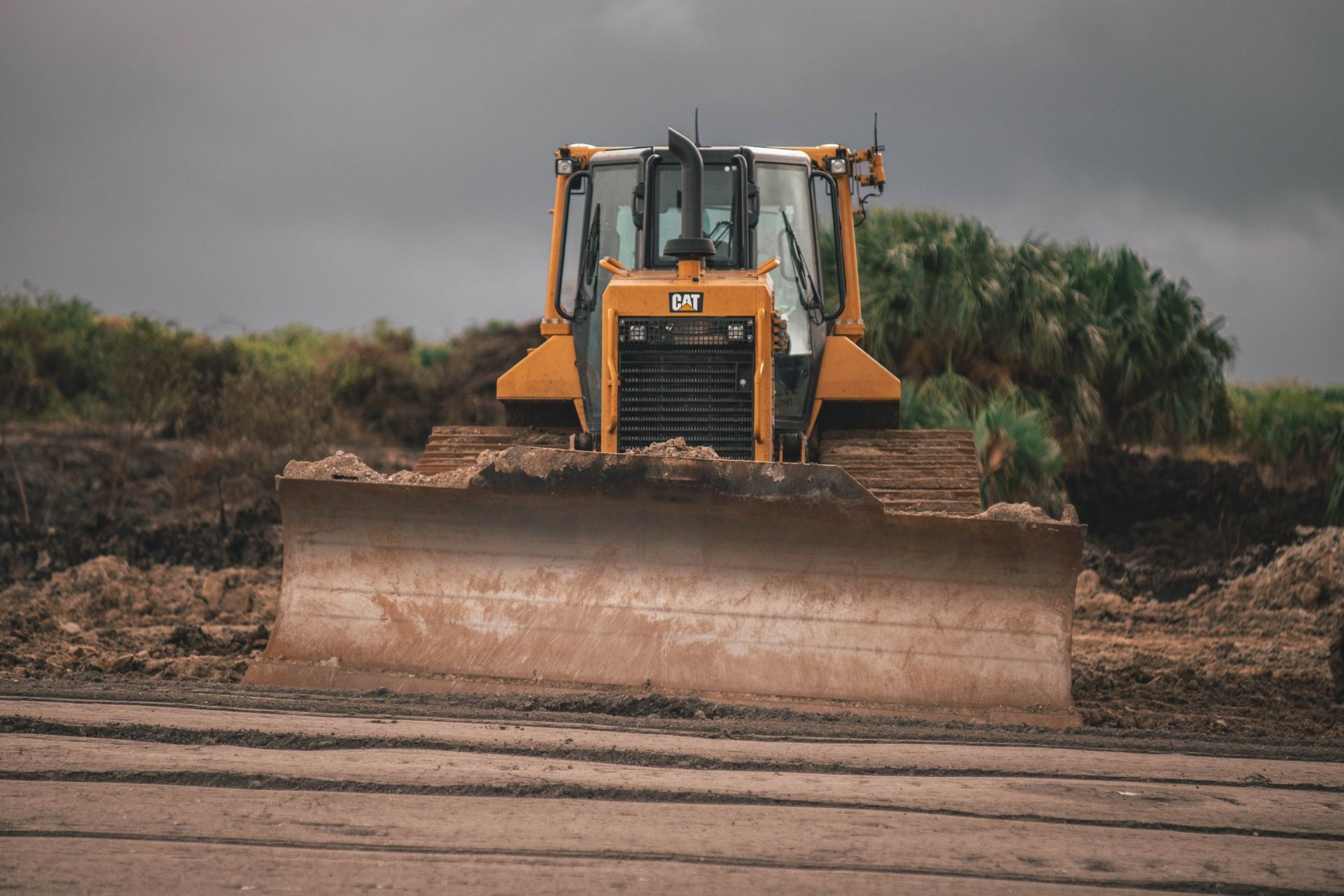 Yellow bulldozer pushing earth on a cloudy day.