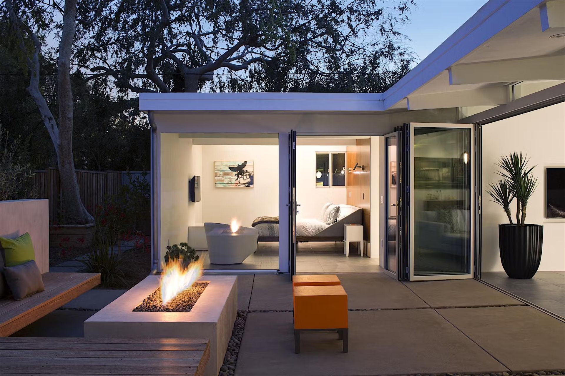 Outdoor patio with fire pit and connected modern home with open doors.