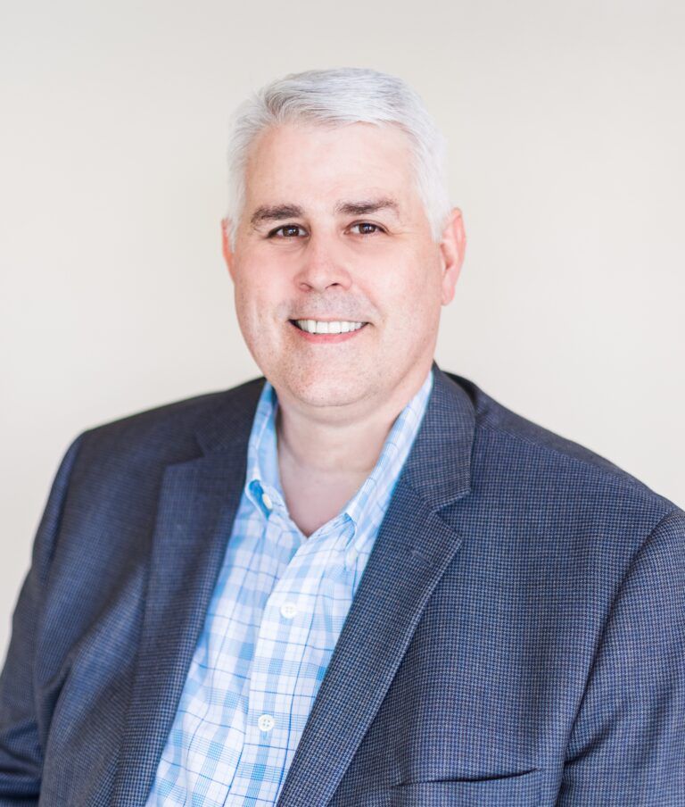 A man in a white shirt and tie is smiling