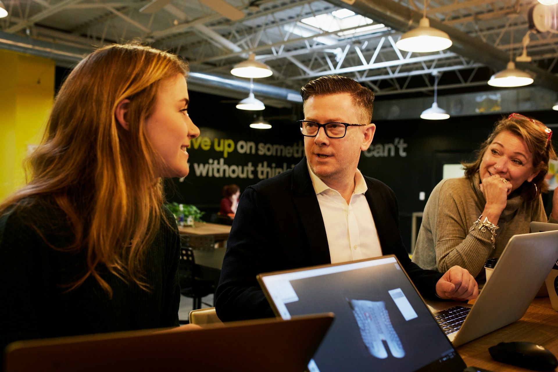 A group of people are sitting at a table with laptops.
