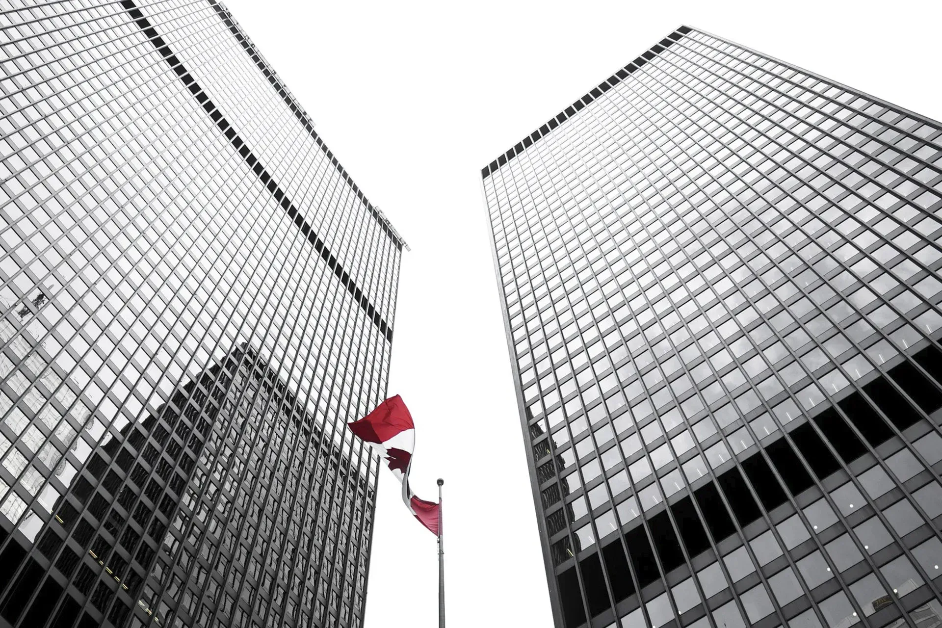 The Canadian flag flying in between two tall buildings.