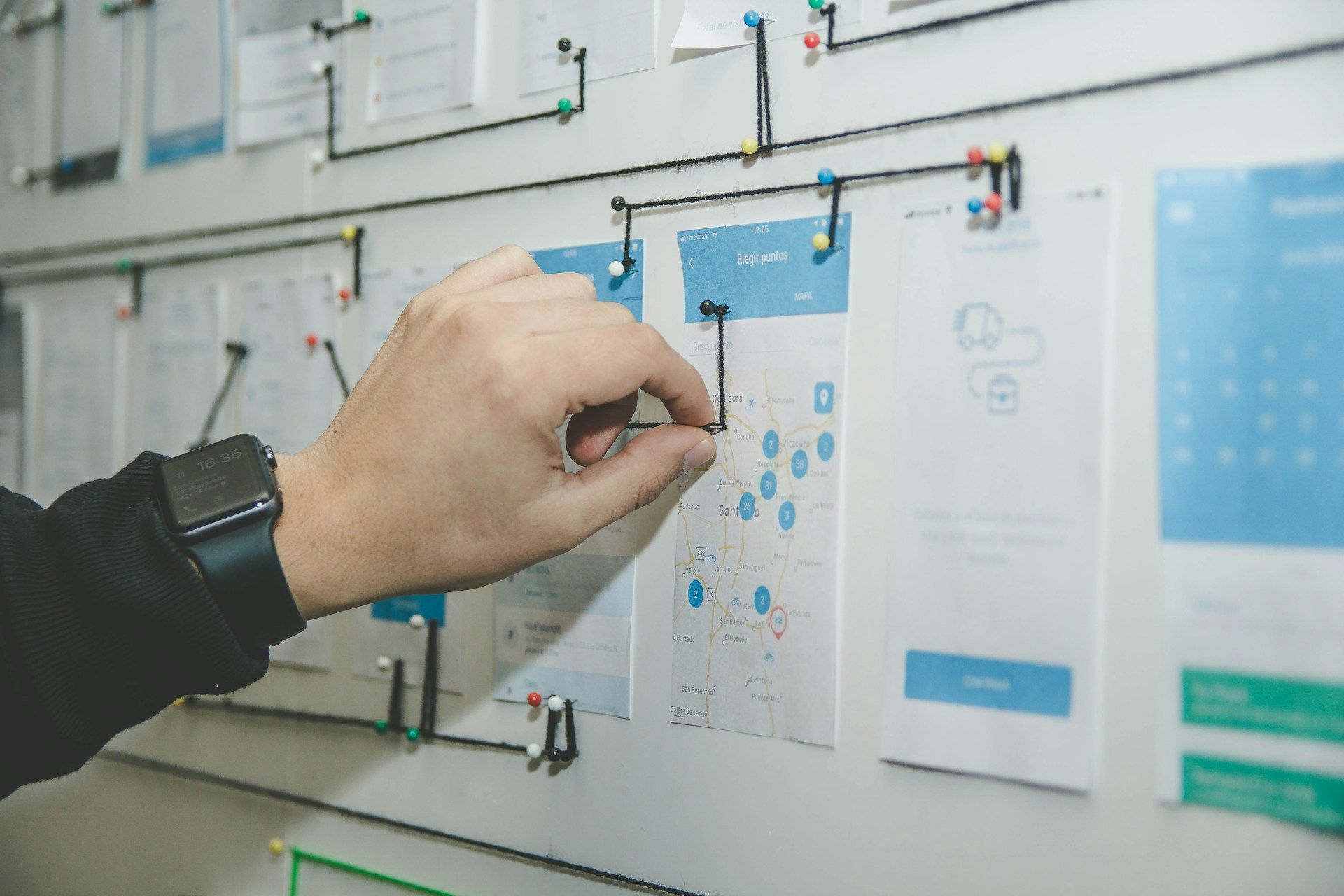 A person is pinning a piece of paper to a whiteboard.