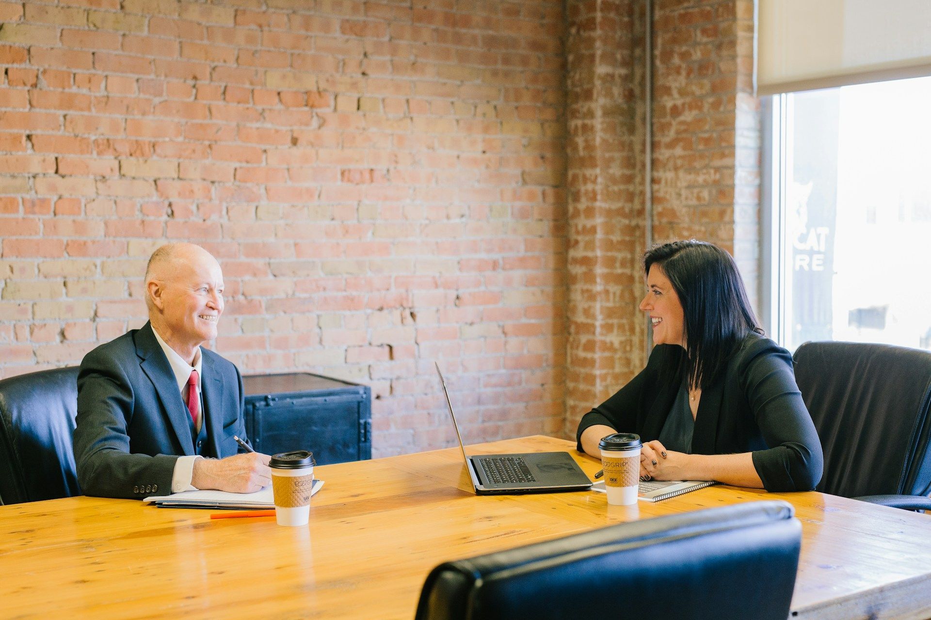 An image of a businessman and a businesswoman sitting at a table in corporate setting