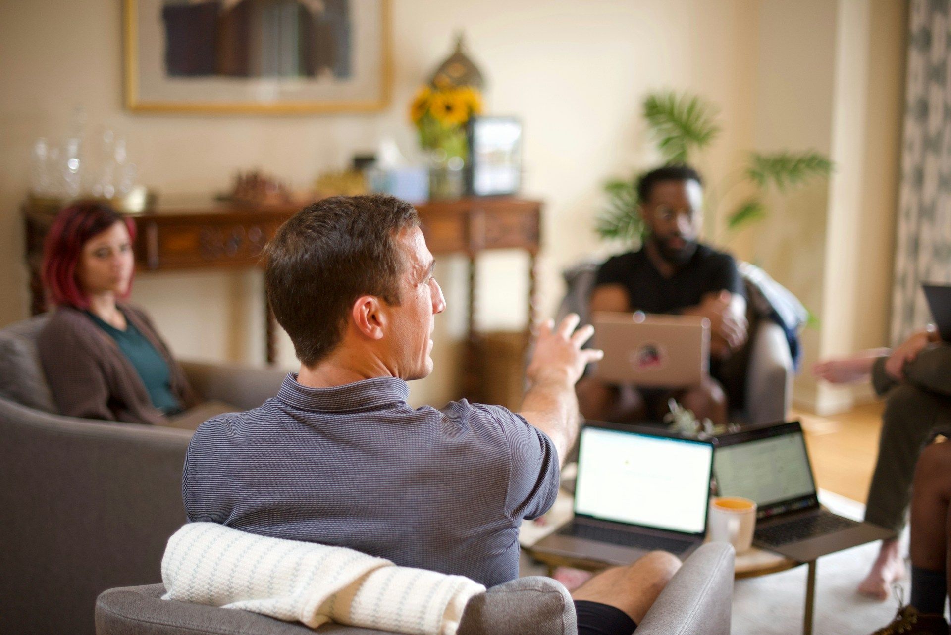 A group of people are sitting in a living room with laptops.