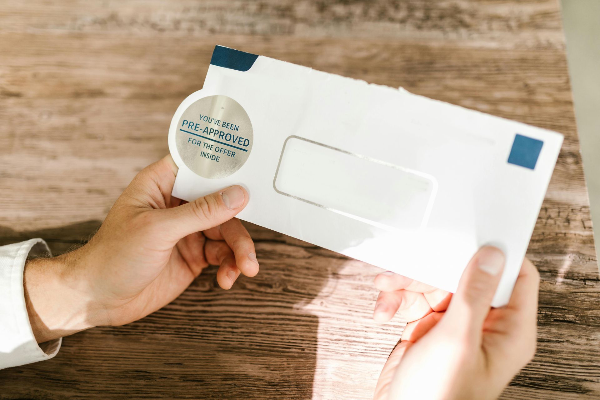 A person is holding an envelope with a magnifying glass in their hand.