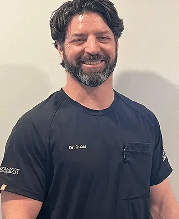 A man with a beard is wearing a black shirt and smiling.
