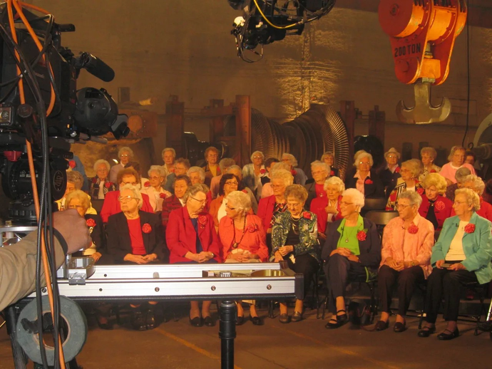 A group of people are sitting in front of a camera with a hook that says ' a ' on it