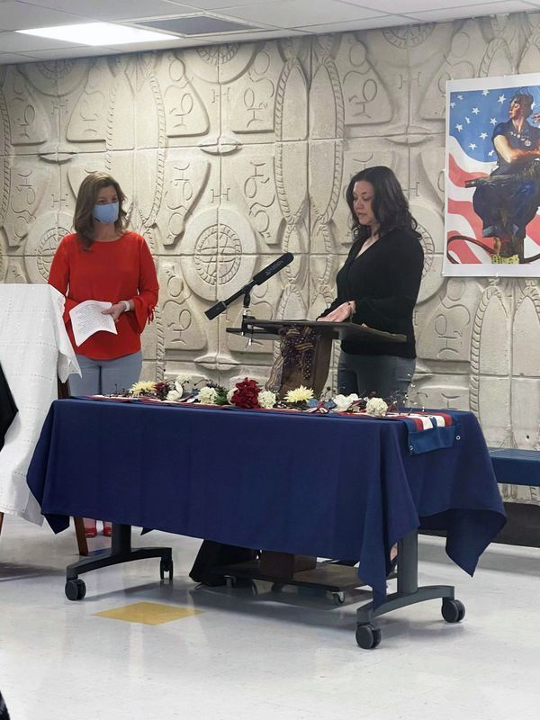 Two women are standing in front of a table with a blue table cloth.