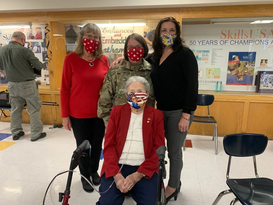 A group of people wearing face masks are posing for a picture.