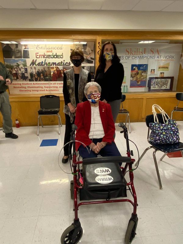 An elderly woman is sitting in a walker wearing a mask.