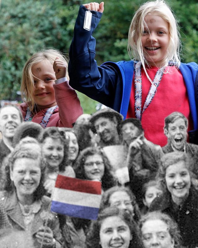 A girl holds up a medal in front of a group of people
