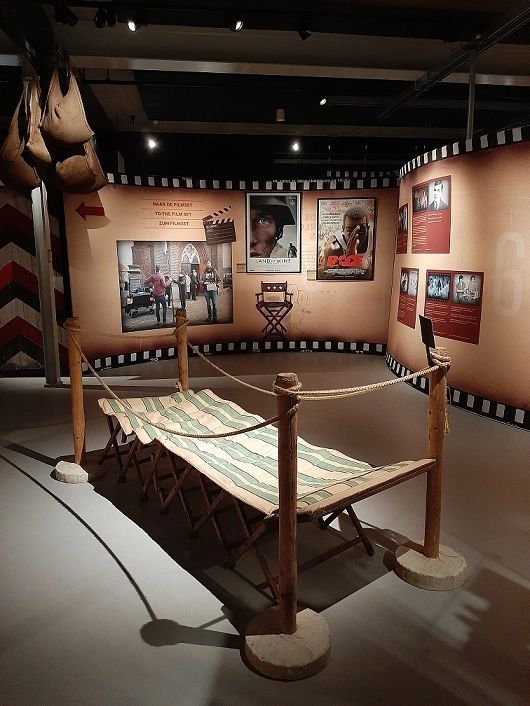 A rope fence surrounds a bed in a room with posters on the wall