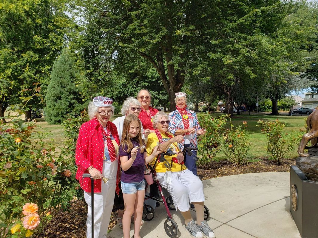 A group of people are posing for a picture in front of a statue in a park.