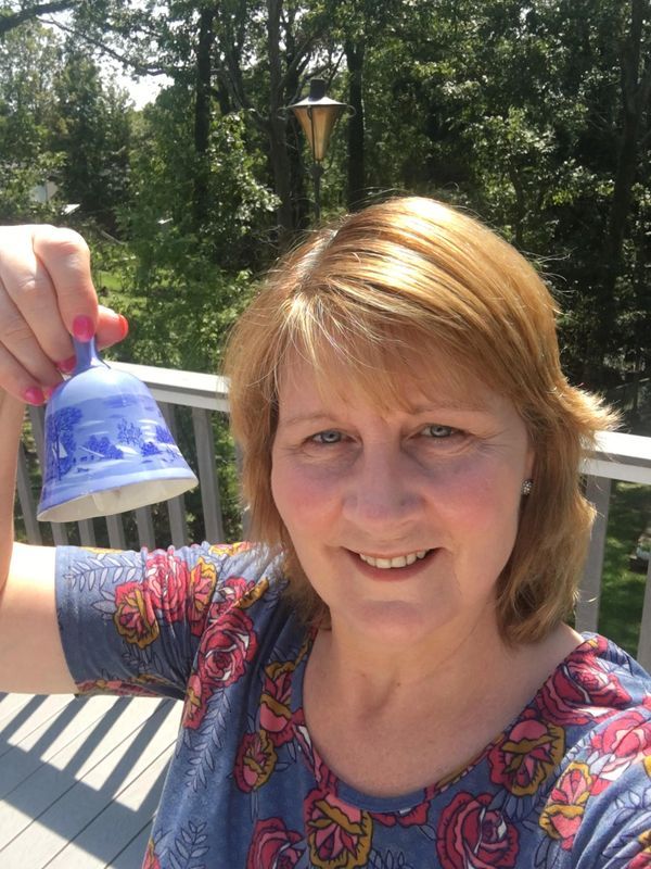 A woman is holding a bell in her hand and smiling.