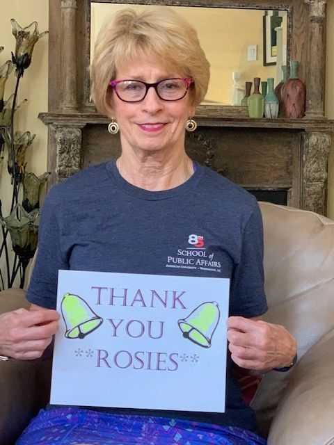 A woman holding a sign that says thank you rosies