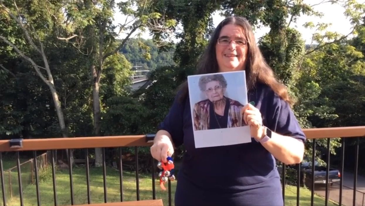A woman is holding a picture of an older woman