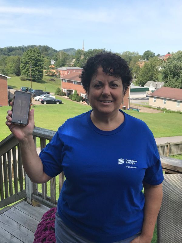 A woman in a blue shirt is holding a cell phone