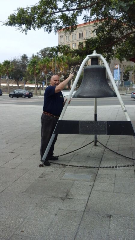 A man is standing next to a large bell
