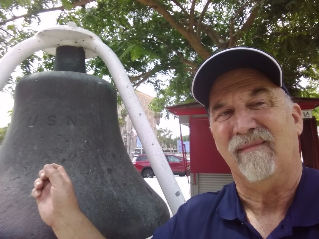 A man with a beard is holding a large bell