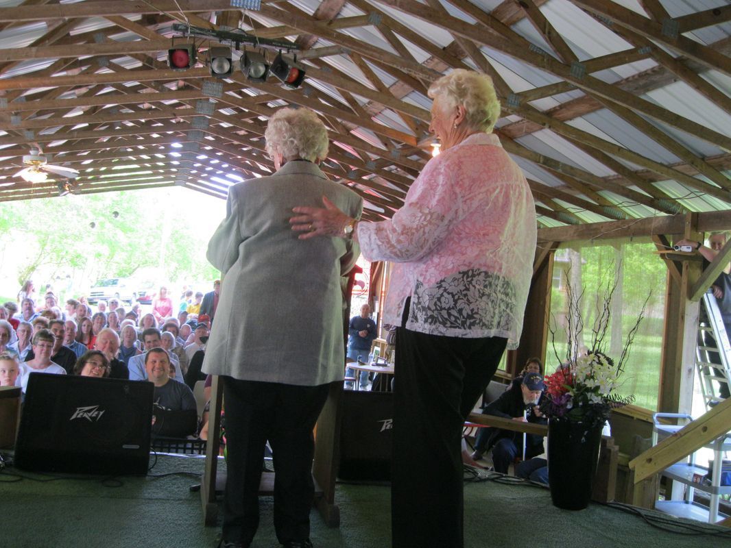 Two older women are dancing in front of a crowd