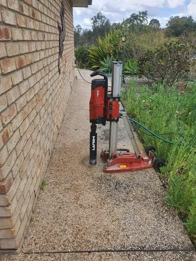 A Machine is Sitting on the Sidewalk Next to a Brick Wall — Superior Termite & Pest Control in Bundaberg, QLD