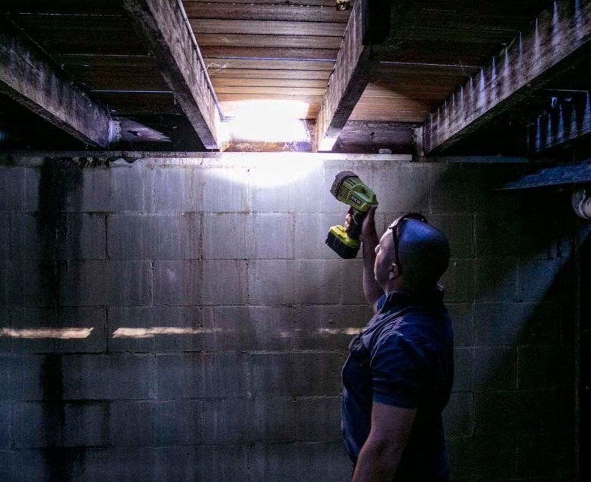 A Man is Holding a Flashlight in a Dark Room — Superior Termite & Pest Control in Bundaberg, QLD