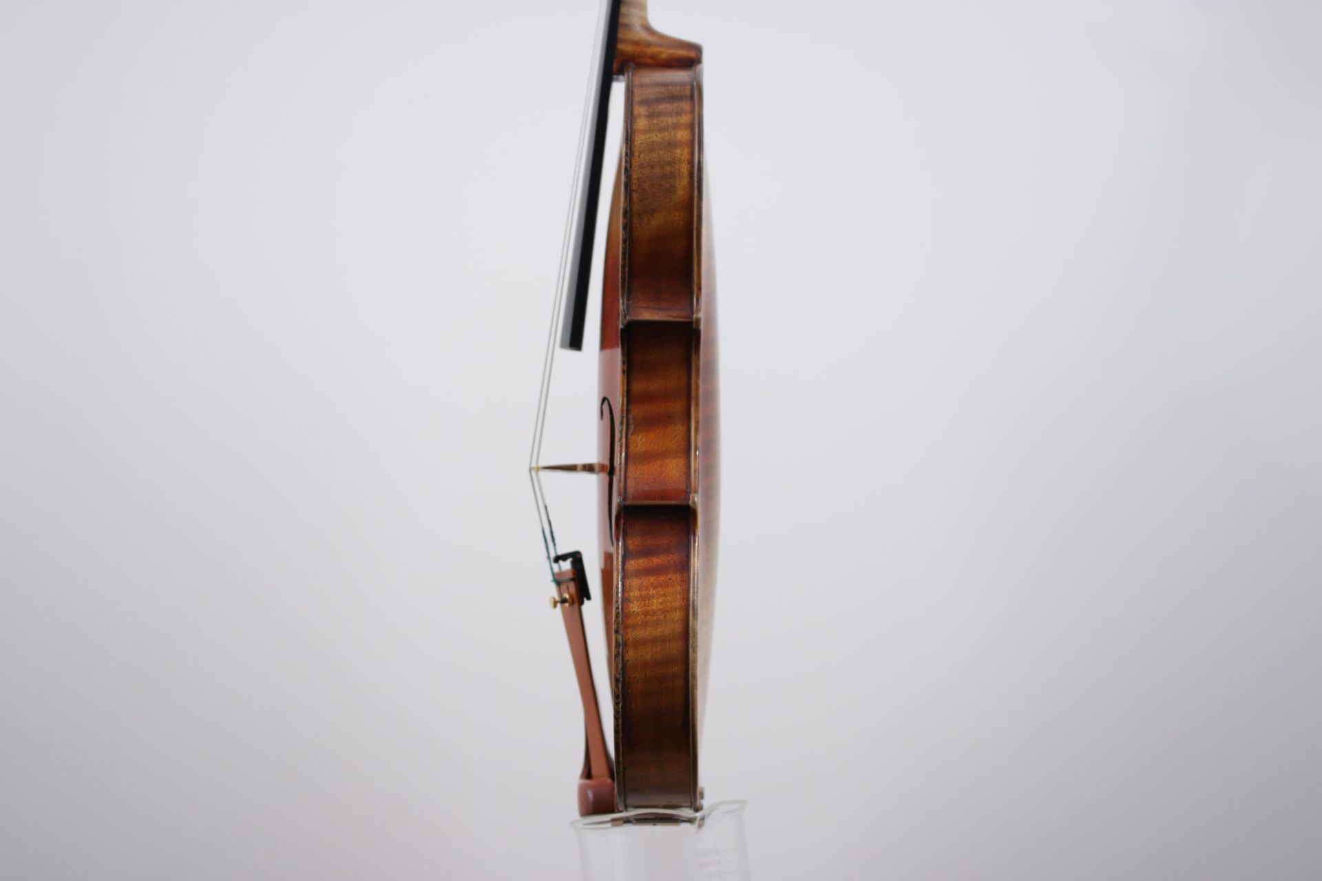 A violin with a bow is sitting on a white surface.