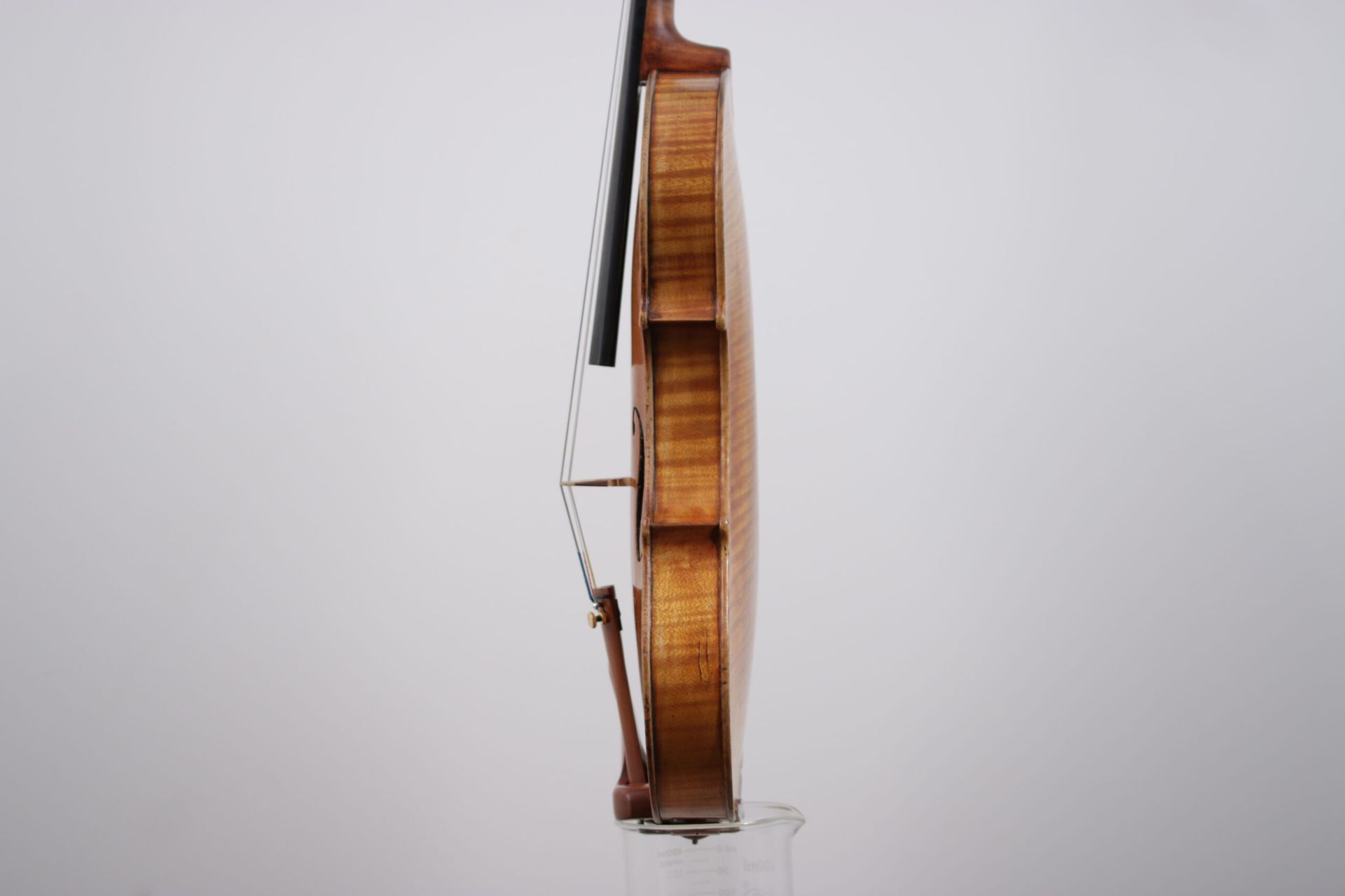A violin is sitting on top of a glass on a white background.