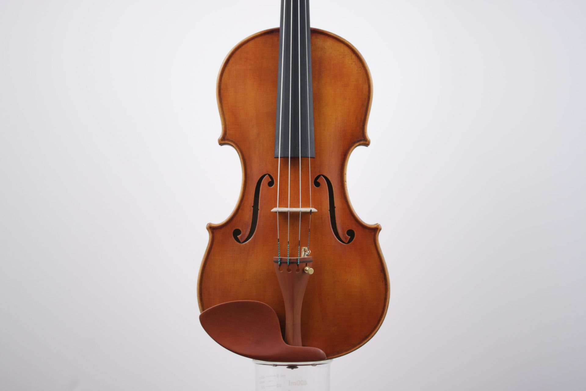 A violin is sitting on a white surface.