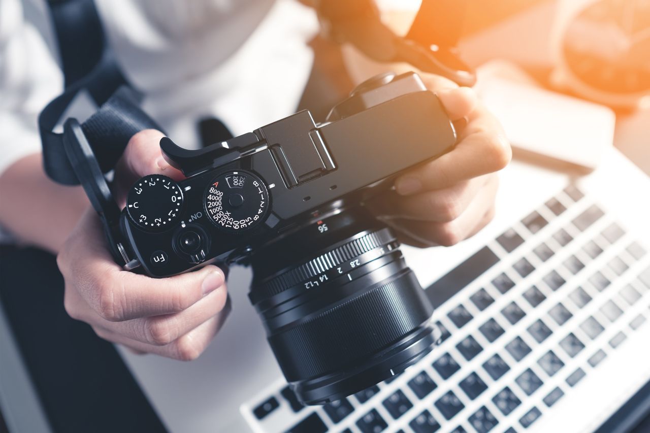 A person is holding a camera in front of a laptop keyboard.
