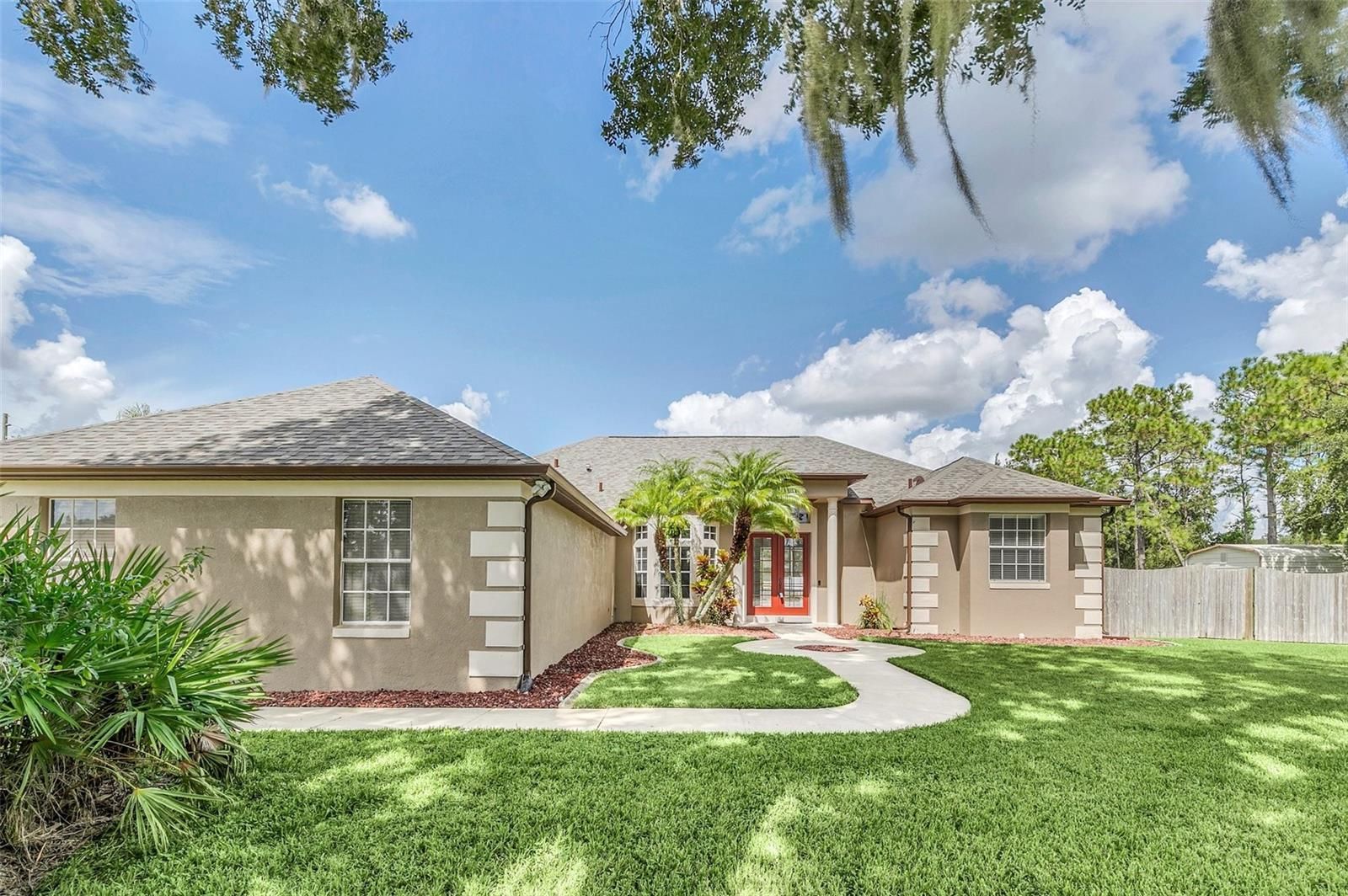 A house with a lush green lawn and a red door