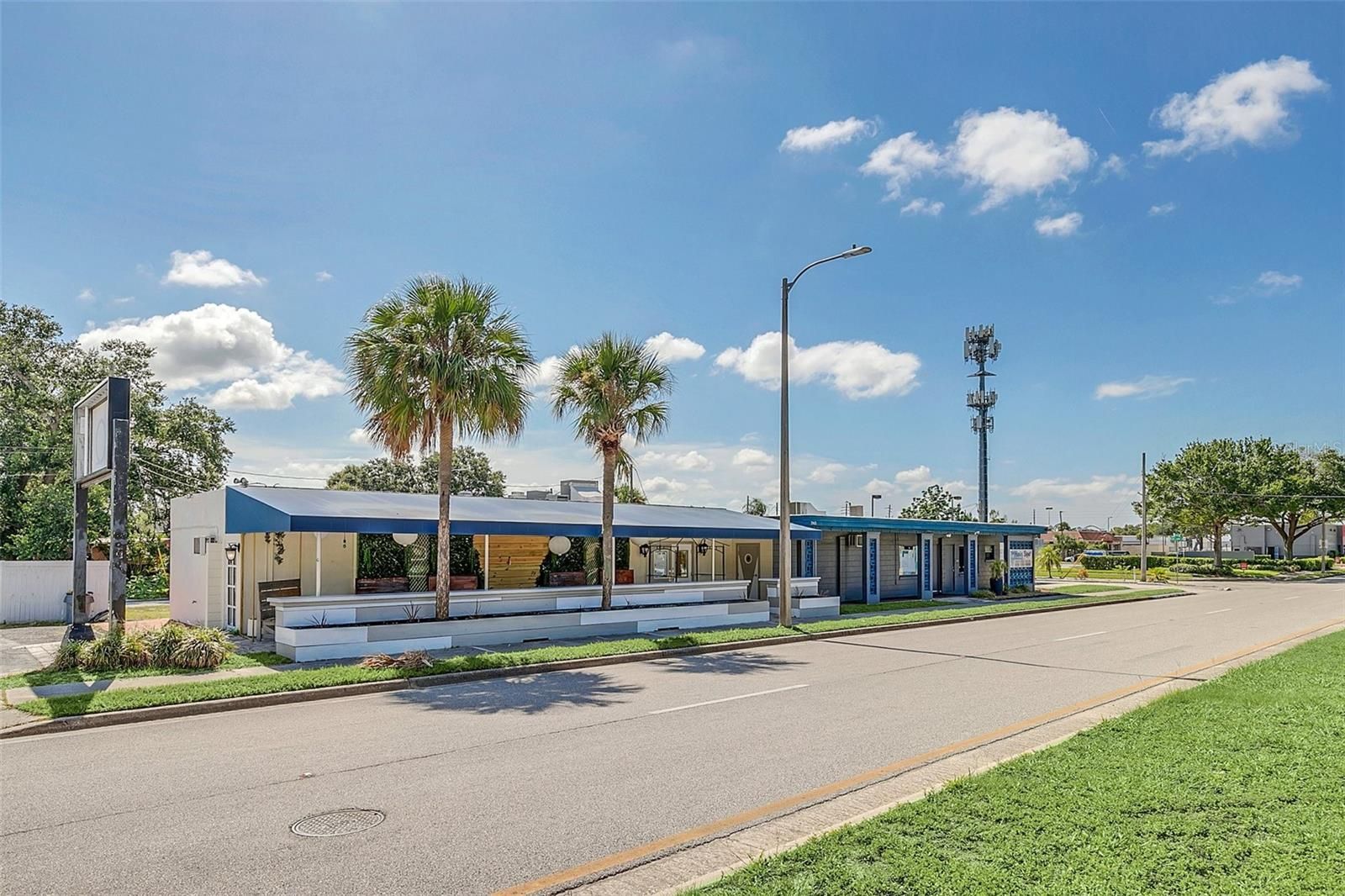 A large white building with a blue awning is sitting on the side of a road.