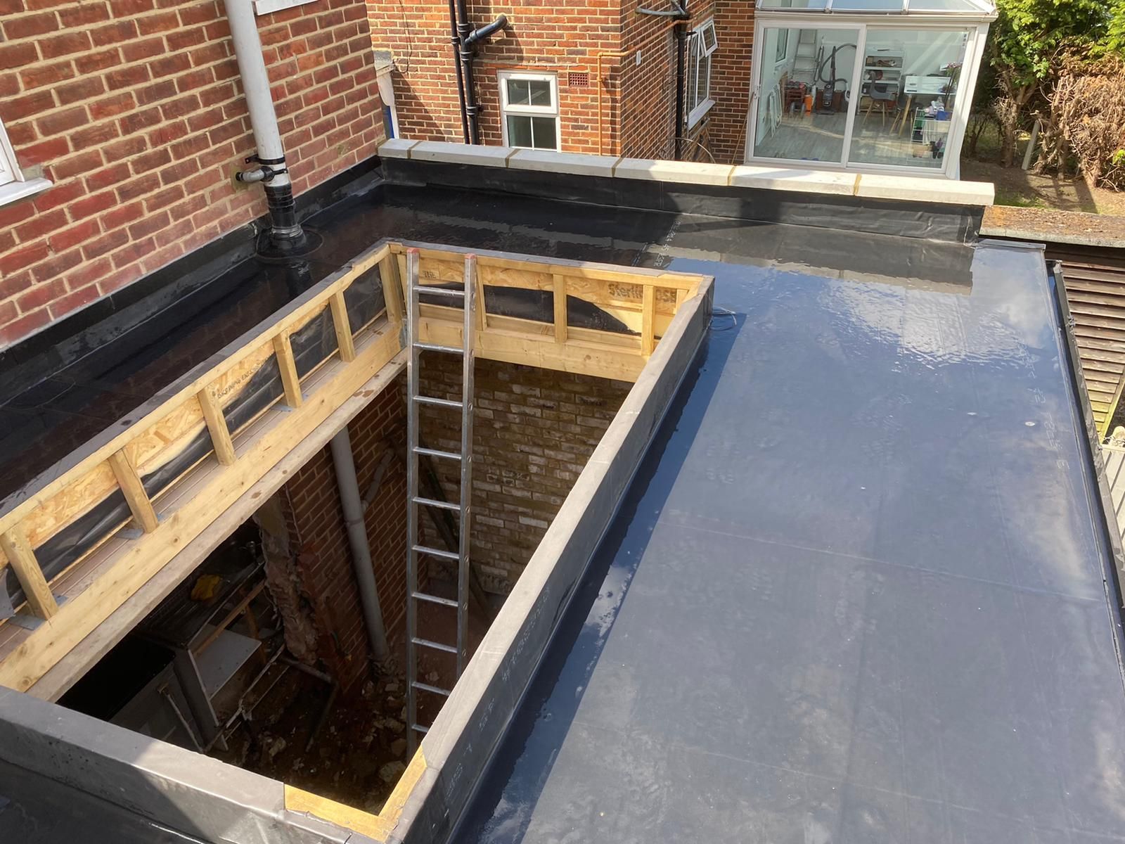 A ladder is sitting in a hole in the roof of a house.