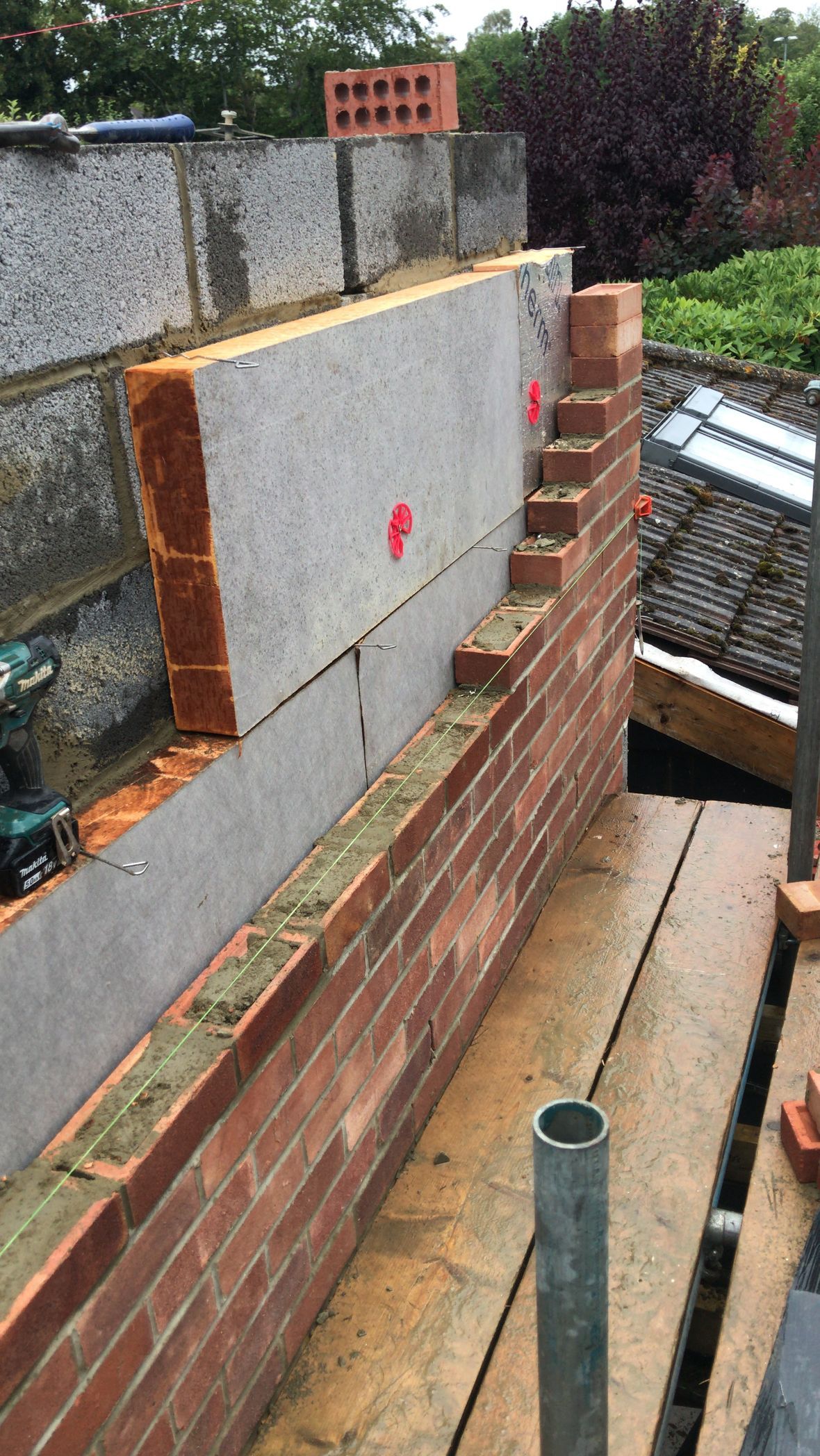 A brick wall is being built on a scaffolding.