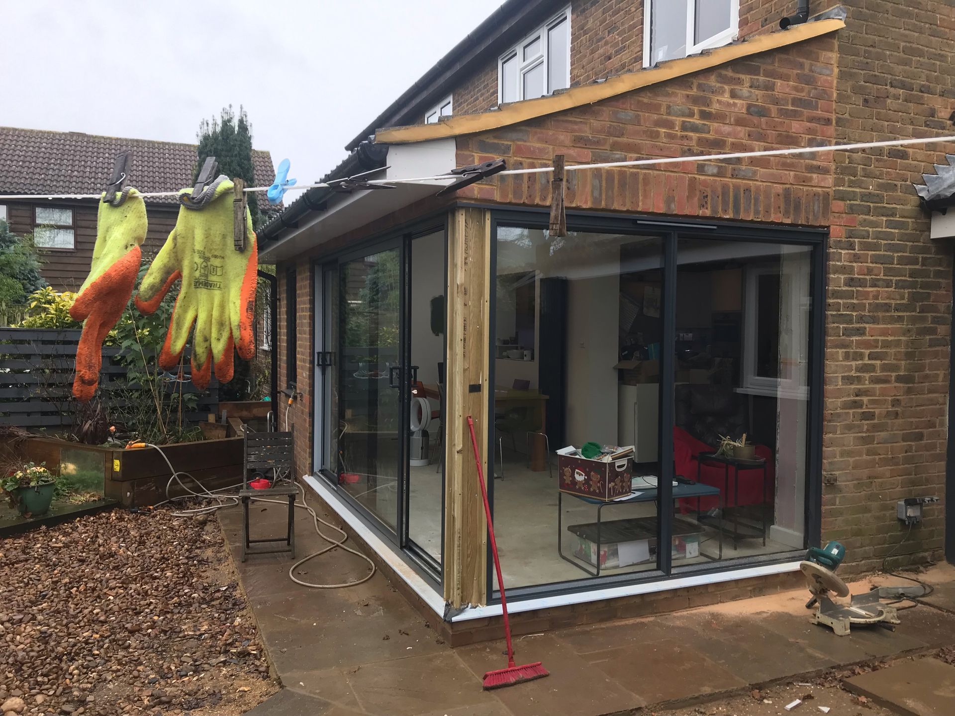A couple of gloves are hanging on a clothes line in front of a house.
