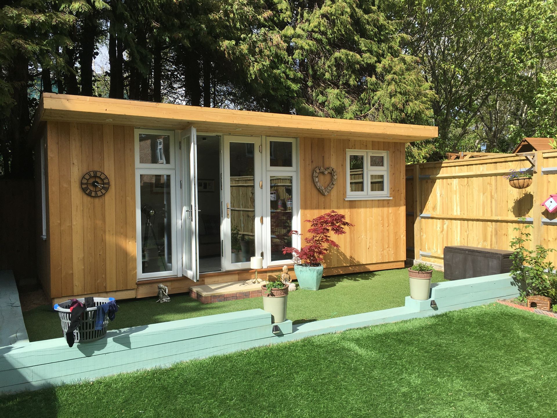 A small wooden house is sitting in the middle of a lush green yard.