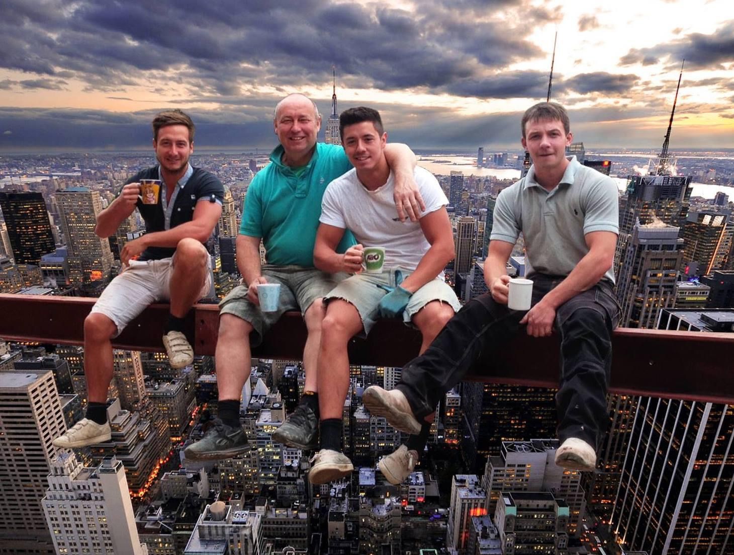 A group of men are sitting on a ledge overlooking a city.