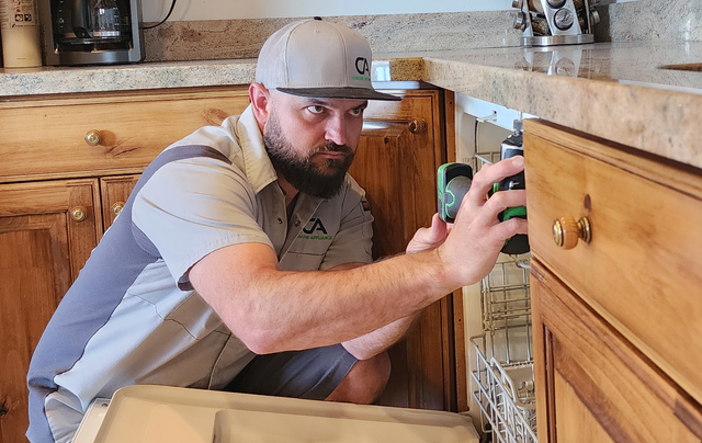 A man is working on a dishwasher in a kitchen.
