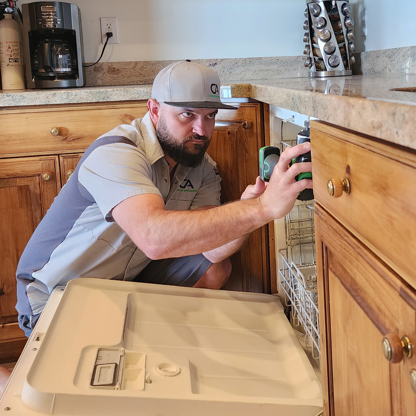 A man is working on a dishwasher in a kitchen