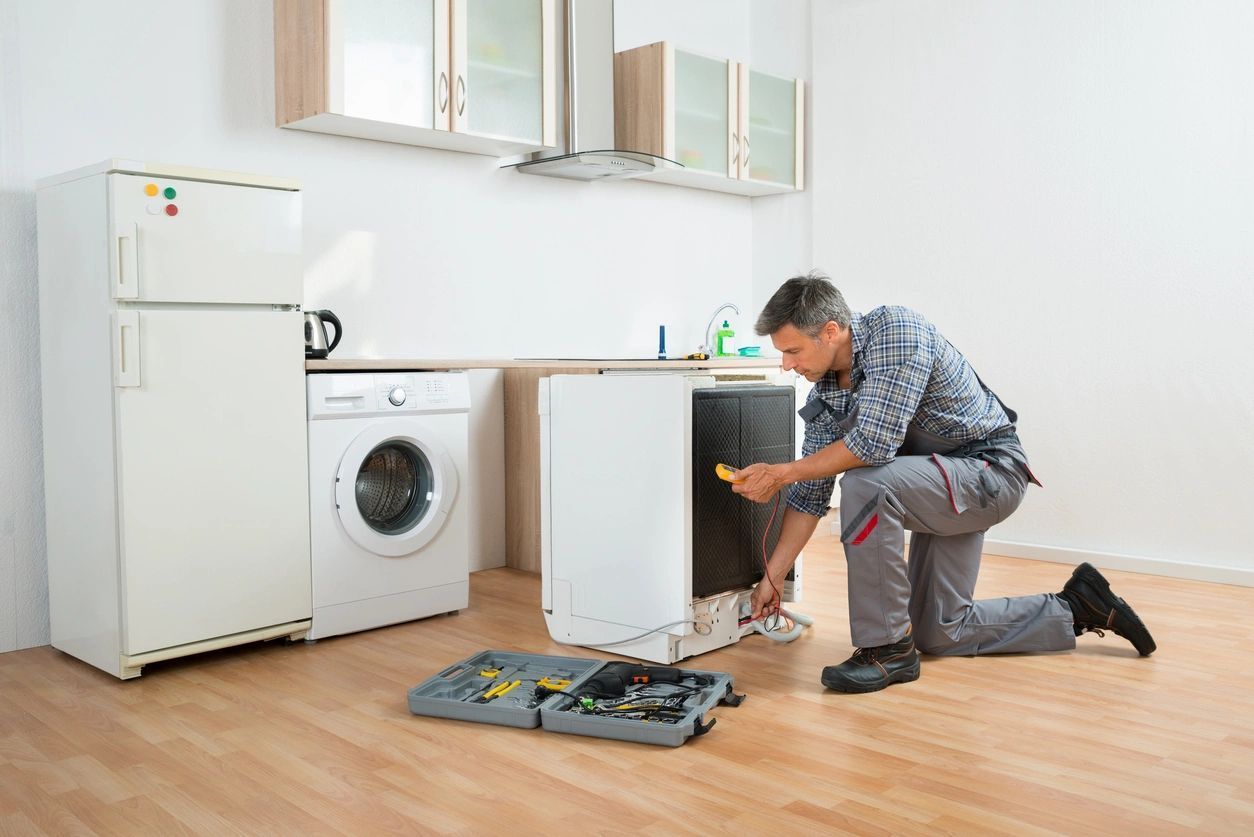 A man is fixing a washing machine in a kitchen.